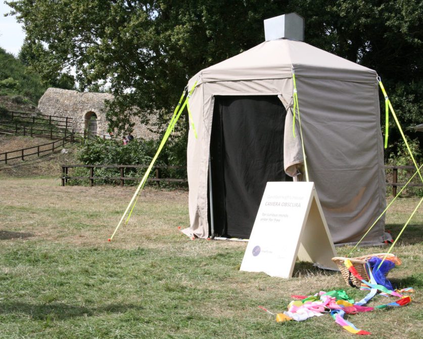An image of the nomadica camera obscura in action. A small tent is erected in a field.