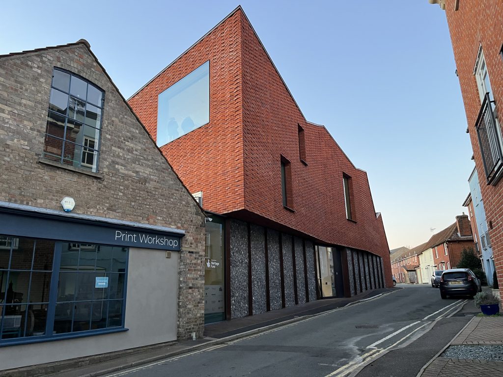 An image taken on Weavers Lane of the new galleries at Gainsborough's House. The structure is grand with a red-brick facade.