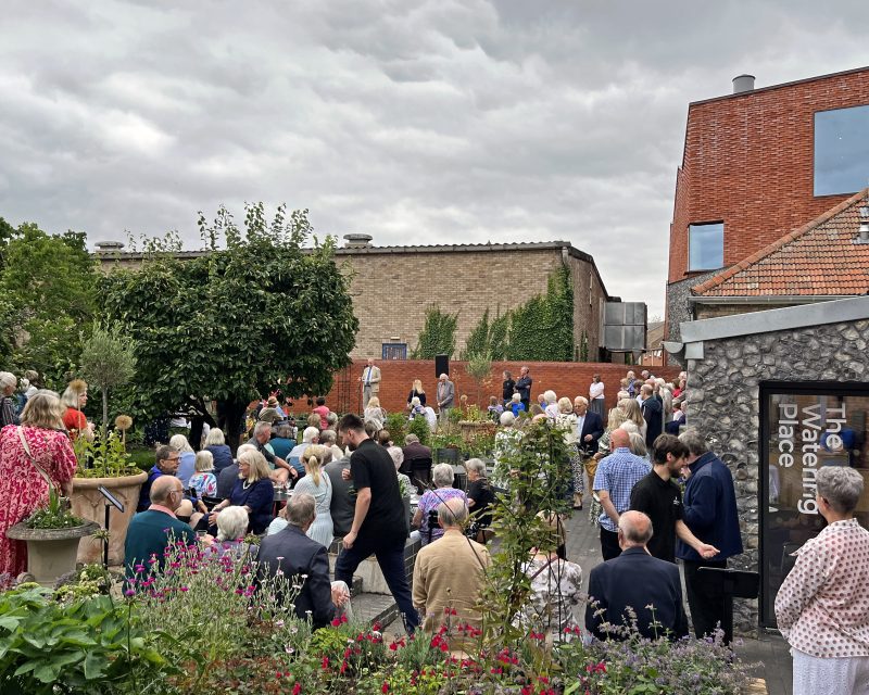 An image of large crowds in the Gainsborough's House walled–gardens. They are listening to Mark Bills give his speech. 