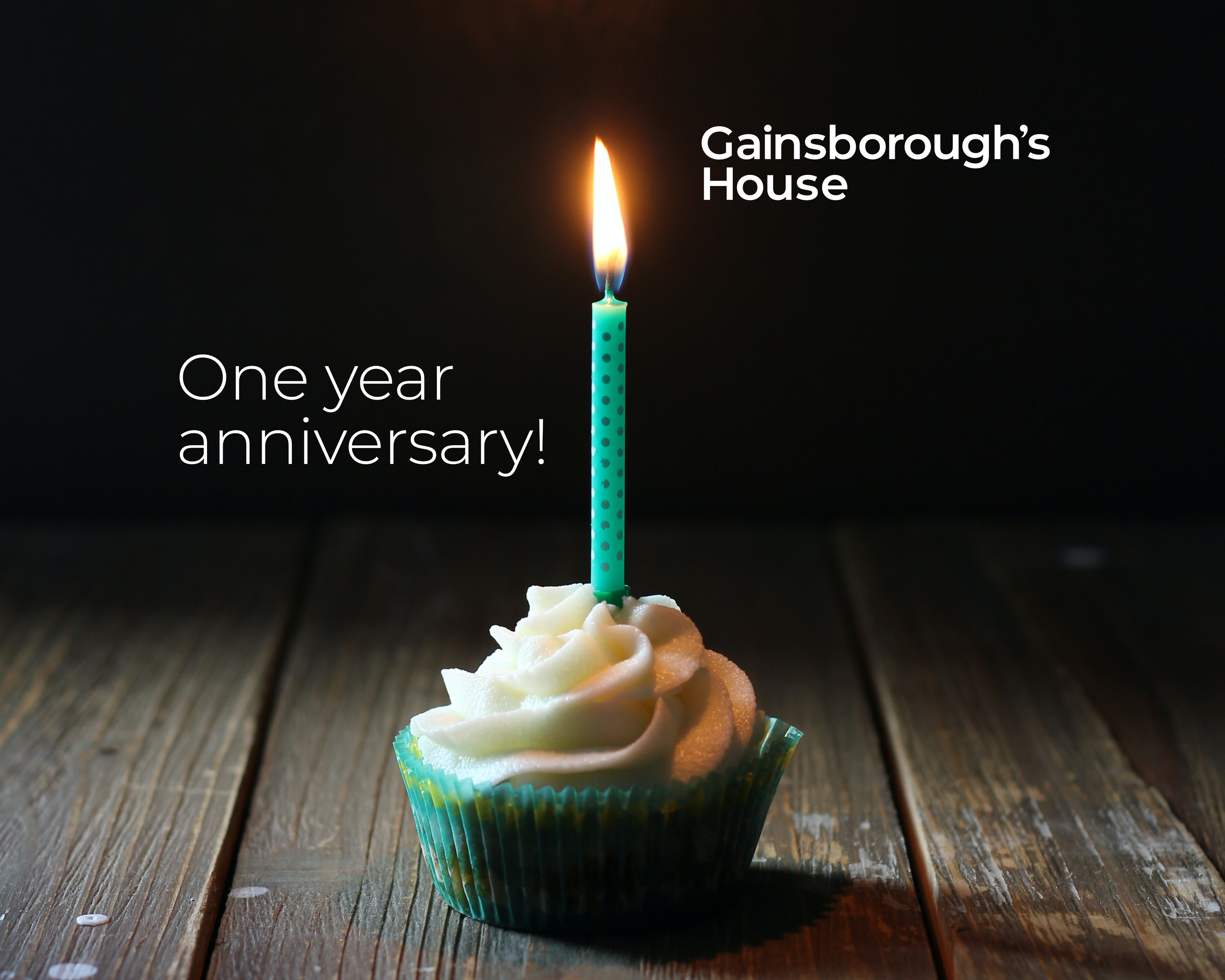 An image of a cupcake with a lit candle in it. There is overlayed text which reads: One year anniversary. The Gainsborough's House logo is in the top right corner.