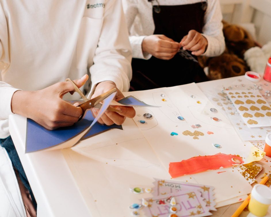 An image of two children cutting and sticking craft items.
