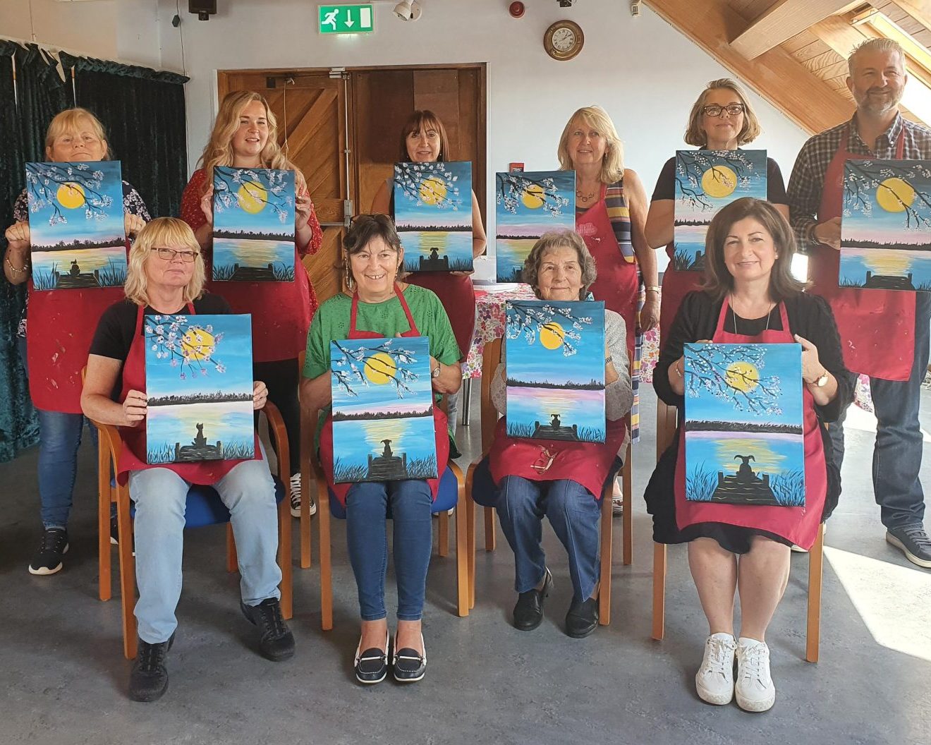 An image of several individuals holding up handpainted canvases.