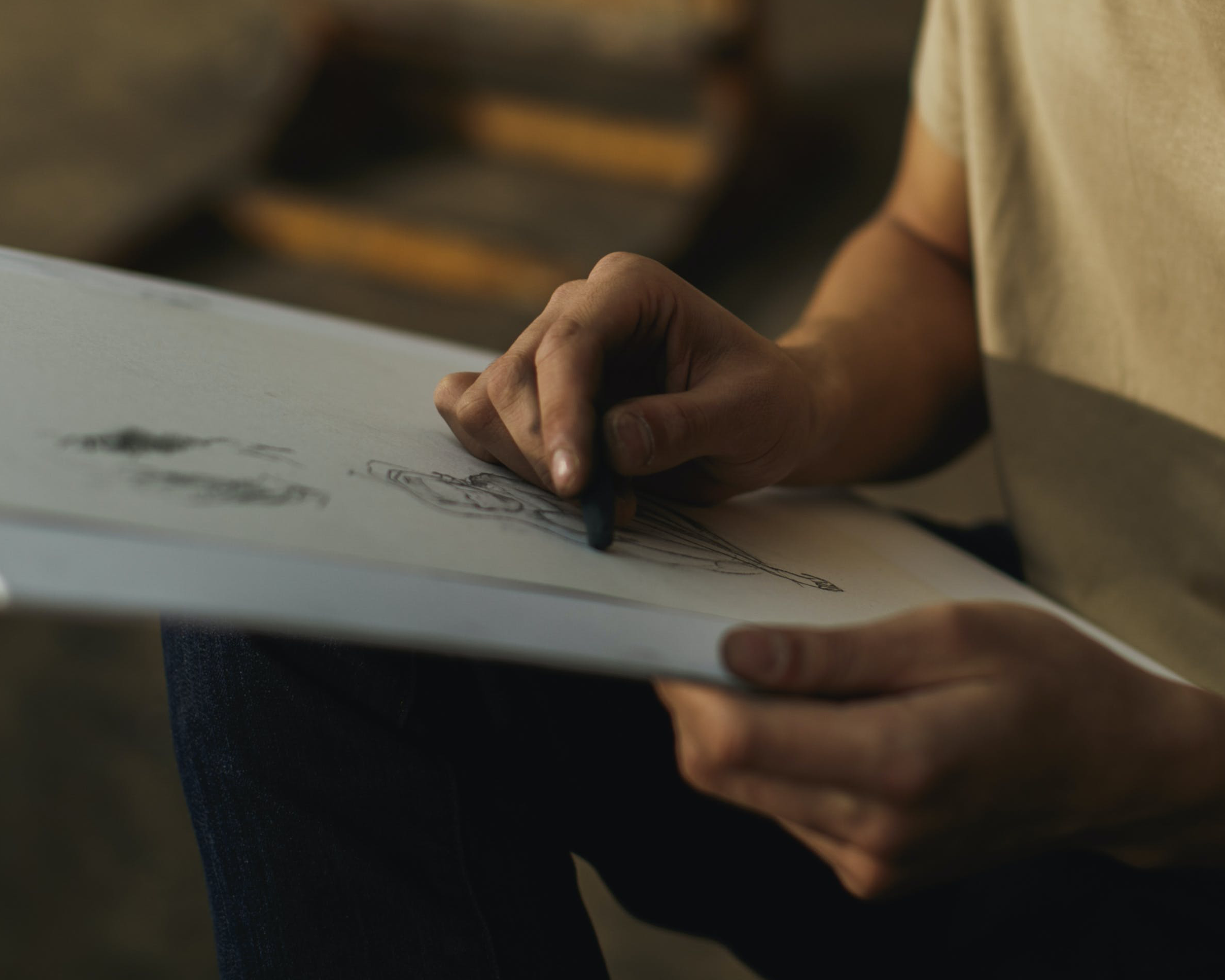 An image of a person drawing with charcoal on paper.