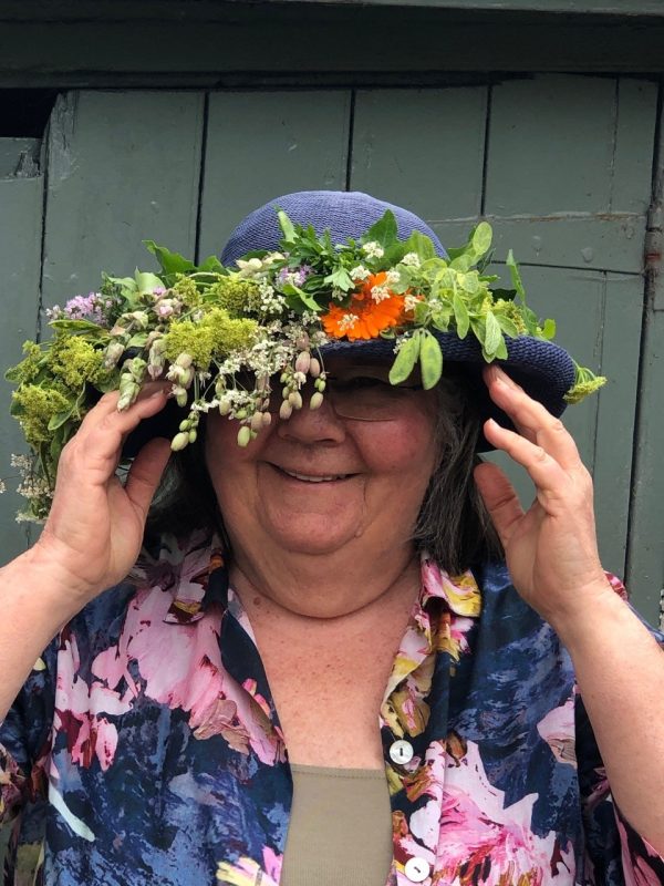 An image of Barbara Segall. A white woman smiling at camera with a floral hat. 