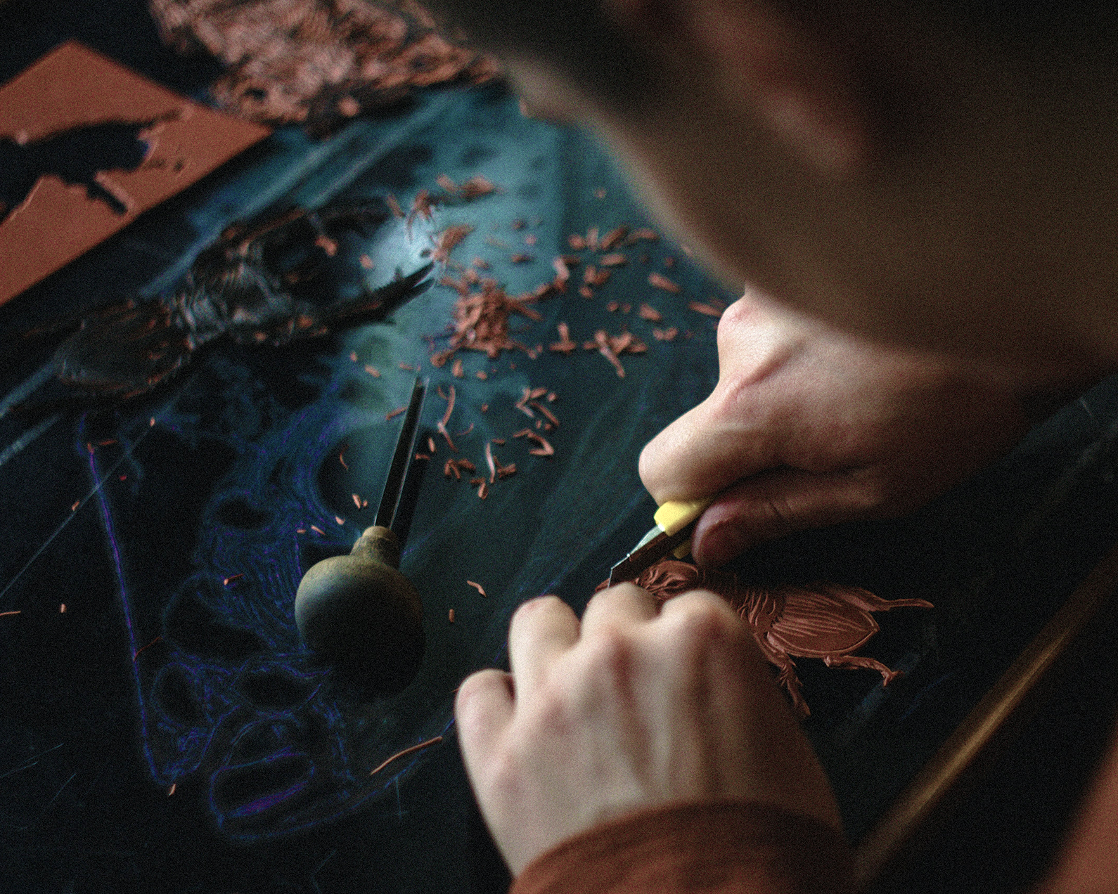 An image of a person using a bulin on a piece of lino.