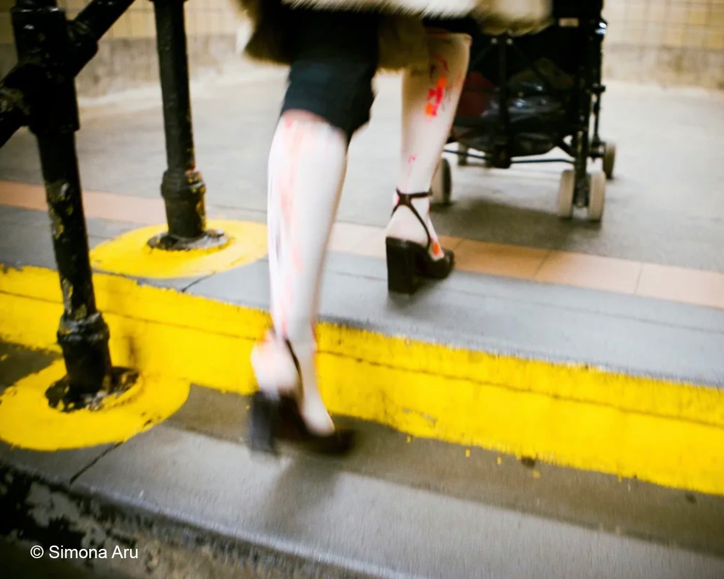 An image of a person in heels stepping onto a foot step with a buggy.