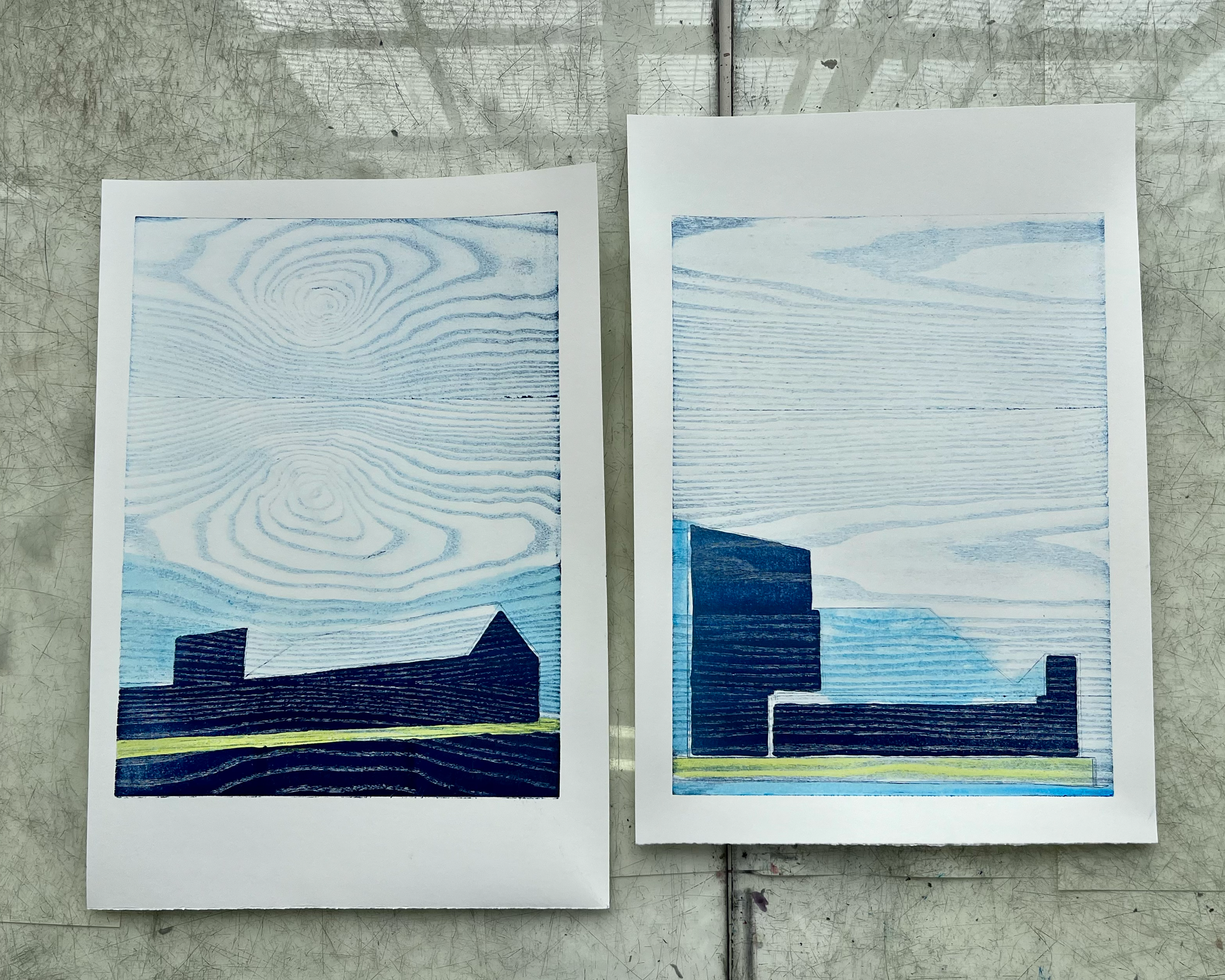 An image of Natasha Marshall's Mokulito prints. They depict simplistic architecture using shades of blue. The sky has a wood grain texture on it.